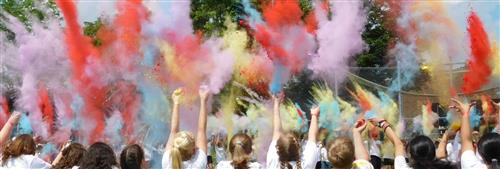 Students throw multi-colored dust into the air